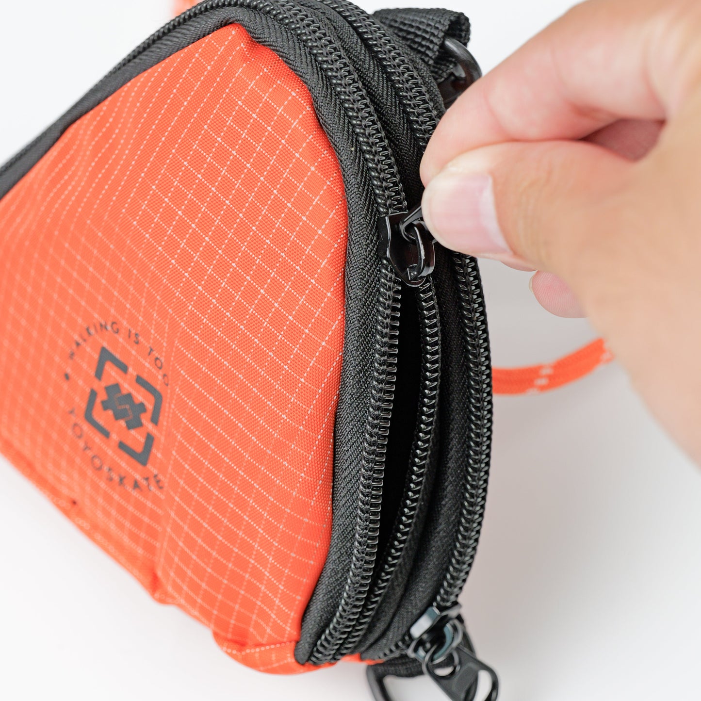 An orange and black zippered pouch with a hand pulling the zipper tab, shown on a clean white background.