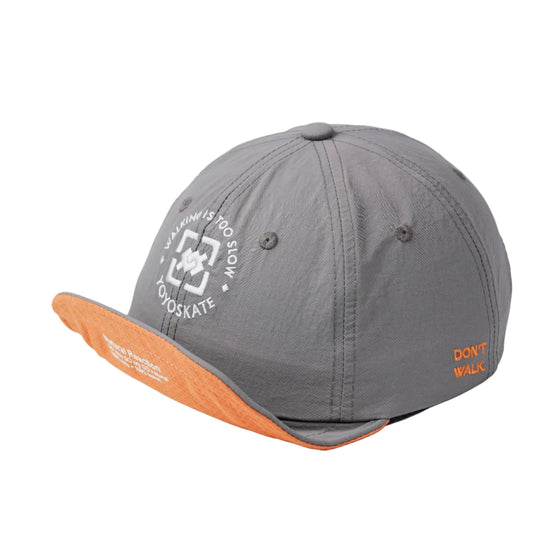 A gray athletic cap with an orange underside on the brim, featuring a white circular logo on the front and orange text on the side, photographed on a white studio background.