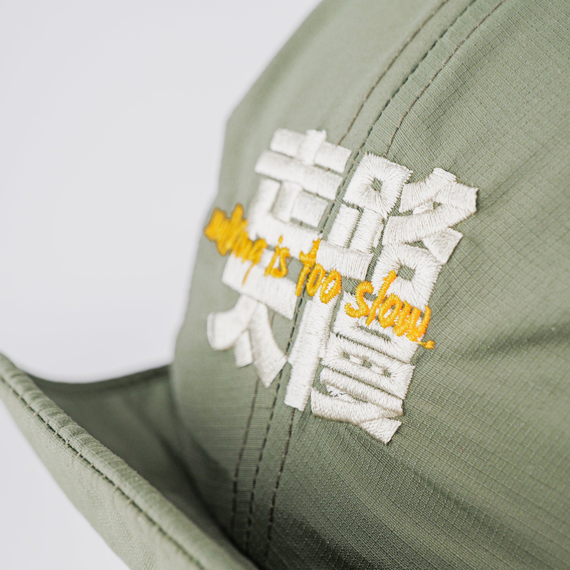 YOYOSKATE cap with white embroidered Chinese characters and yellow script reading 'moving is too slow.' on a light gray background.